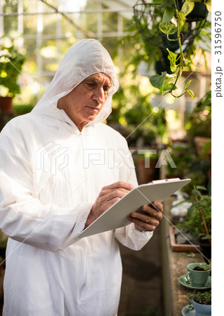 Male scientist writing on clipboard while examining plants 31596750