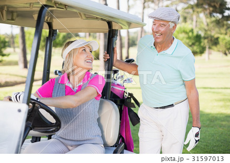Golfer woman looking at man while sitting in golf buggy Golfer woman looking at man while sitting in golf buggy 31597013