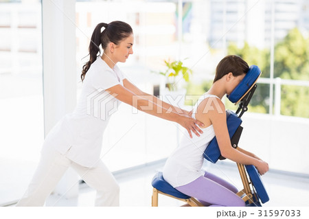 Woman being massaged on chair by masseuse 31597033