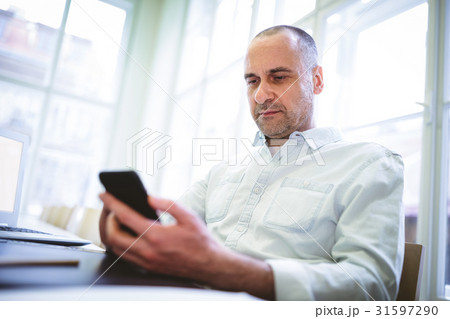 Serious businessman using mobile phone Serious businessman using mobile phone 31597290