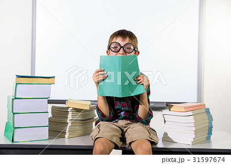 Happy boy holding book while sitting in classroom 31597674