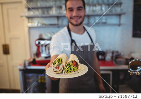 Portrait of happy waiter serving rolls at cafeteria 31597712