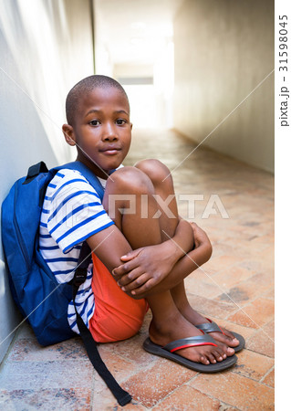 Elementary boy sitting on corridor in school 31598045