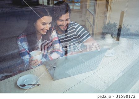 Happy couple using laptop at cafe 31598172