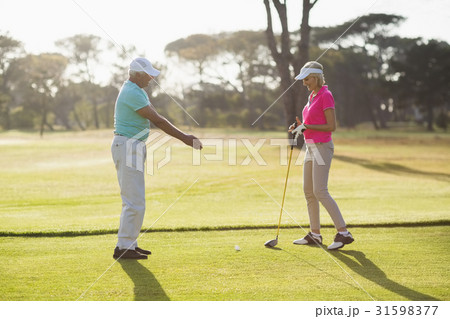 Side view of mature male golf player teaching woman Side view of mature male golf player teaching woman 31598377