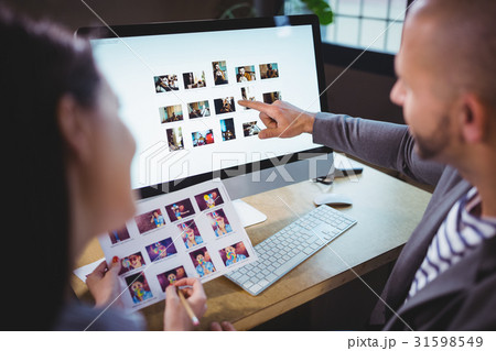 Photo editors discussing over computer in creative office 31598549