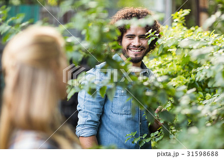 Male gardener looking at woman standing by plants 31598688
