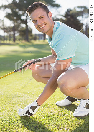 Portrait of confident golfer man placing golf ball on tee 31599248