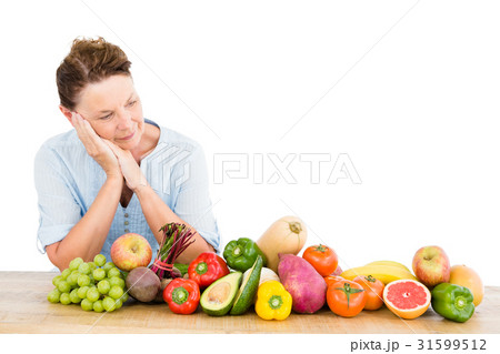 Thoughtful woman standing by fruits and vegetables 31599512
