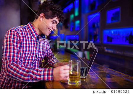 Smiling man using laptop at bar counter 31599522
