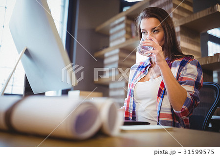 Businesswoman looking at computer while drinking water Businesswoman looking at computer while drinking water 31599575