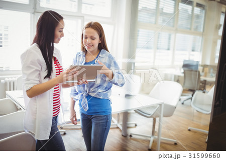 Female colleagues discussing with digital tablet in creative office Female colleagues discussing with digital tablet in creative office 31599660