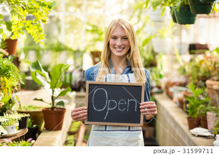 Young woman holding open sign placard at greenhouse 31599711