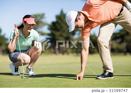 Man removing golf ball from hole Man removing golf ball from hole 31599747