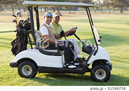 Happy male golfer friends sitting in golf buggy Happy male golfer friends sitting in golf buggy 31599756
