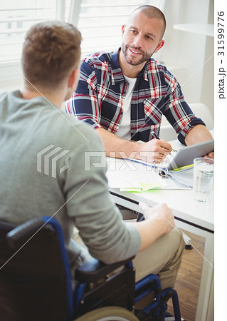 Businessman discussing with handicap colleague in office 31599776