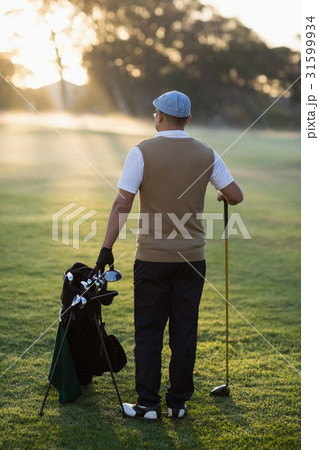Rear view of man standing at golf course 31599934