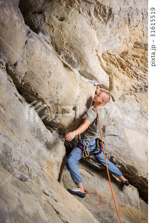 Male climber climbing big boulder with rope 31615519