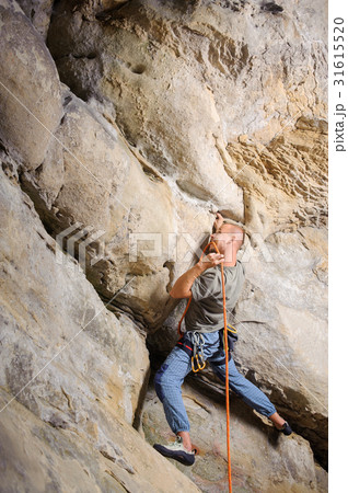 Male climber climbing big boulder with rope 31615520