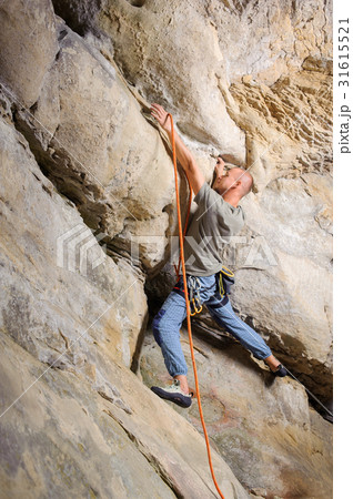 Male climber climbing big boulder with rope 31615521