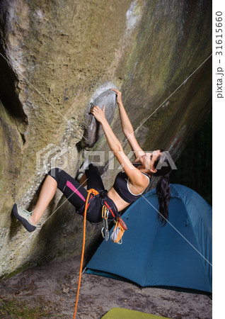 Female climber climbing big boulder with rope 31615660