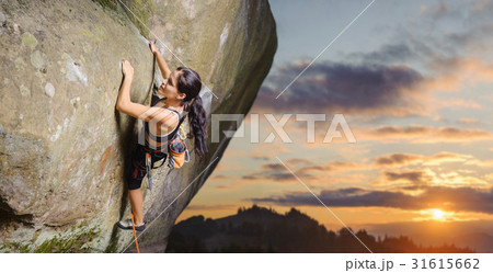 Female climber climbing big boulder with rope Female climber climbing big boulder with rope 31615662