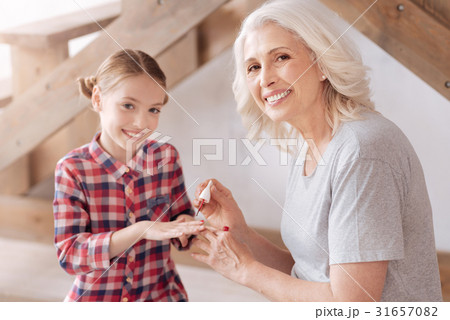Joyful nice woman painting her granddaughters 31657082