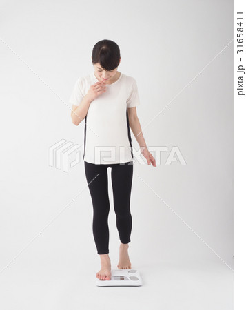 恐る恐る体重計にのる女性 31658411