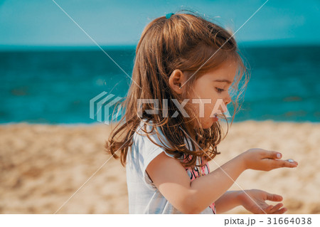 Little girl is holding a sea shell on the beach 31664038