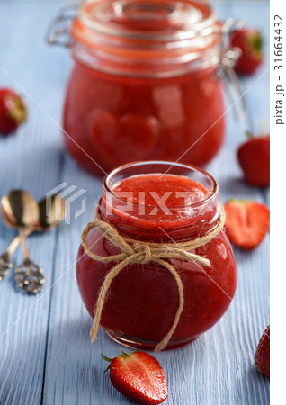 Strawberry jam in glass jar on wooden background. 31664432