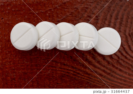 Various white pills on wooden table 31664437