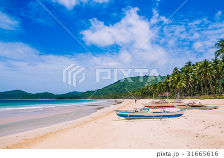 Local boats on wide Nacpan Beach on sunny day. El 31665616