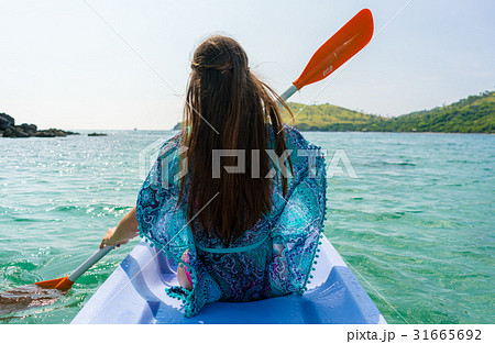 Young woman paddling a canoe along the shore of an Young woman paddling a canoe along the shore of an 31665692