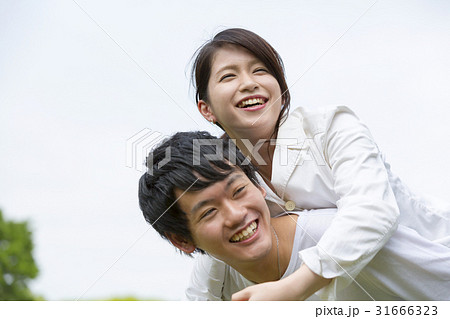 幸せカップル 屋外で彼女を背中におんぶする瞬間イメージの写真素材