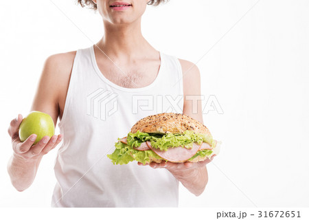 Thin guy choosing between fruit and sandwich 31672651