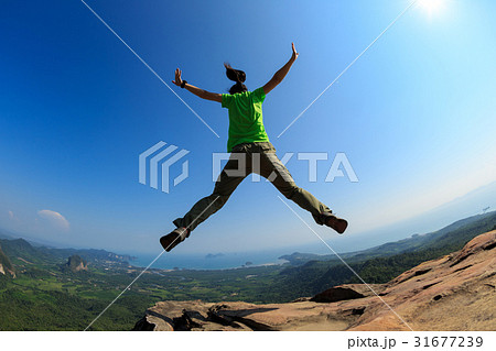 successful woman jumping on rocky mountain peak successful woman jumping on rocky mountain peak 31677239