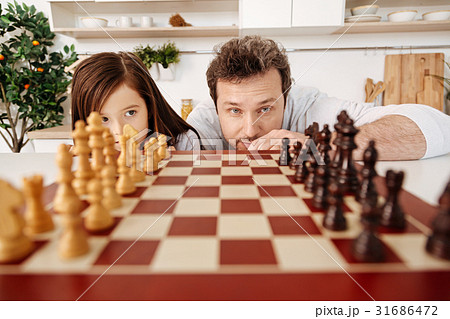 Father and his daughter checking the chess pieces 31686472