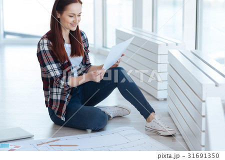 Cheerful nice woman looking at her drawing Cheerful nice woman looking at her drawing 31691350