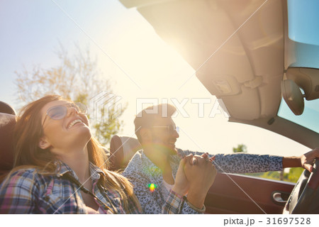 Couple of lovers driving on a convertible car - Couple of lovers driving on a convertible car - 31697528