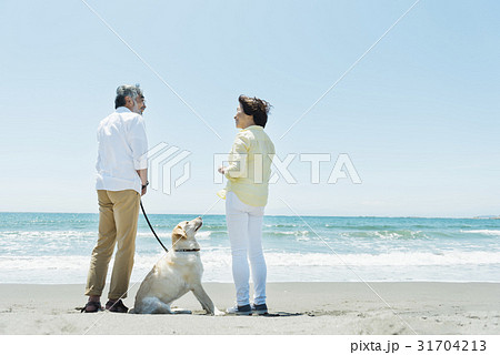 シニア夫婦と犬 浜辺の写真素材