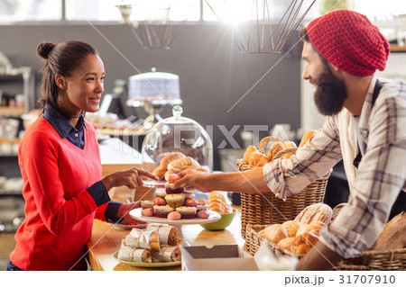 Seller serving a cake to the customer 31707910