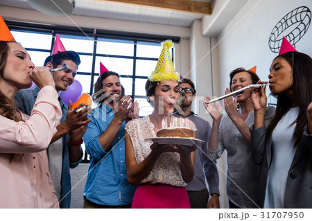 Happy coworker blowing candles for birthday 31707950