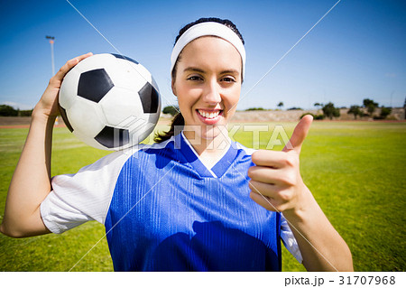 Happy soccer player holding a ball and showing her thumbs up 31707968