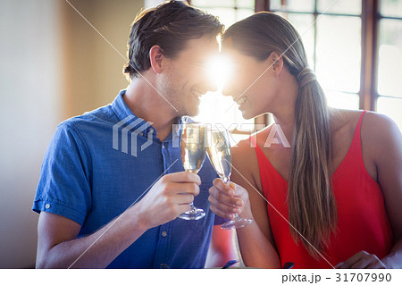 Young couple looking face to face and toasting champagne flutes Young couple looking face to face and toasting champagne flutes 31707990