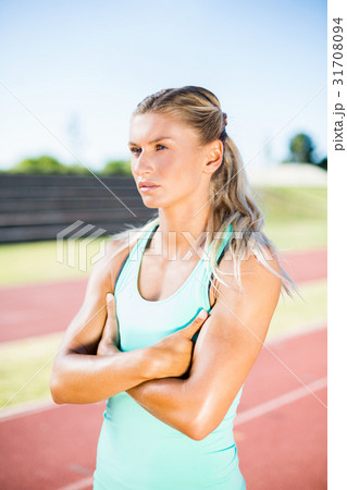 Female athlete standing with arms crossed on the running track 31708094