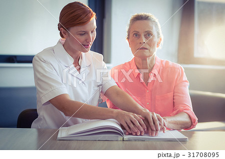Female nurse helping patient in reading the braille book 31708095