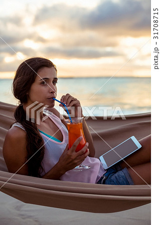 Woman having mocktail while relaxing on a hammock 31708715
