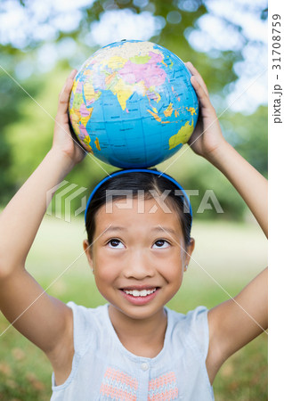 Smiling girl carrying a globe on her head 31708759