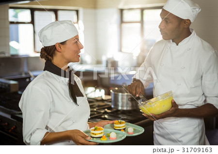 Chefs talking to each other while working in kitchen 31709163