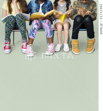 Diverse group of kids sitting in a row reading books Diverse group of kids sitting in a row reading books 31712362